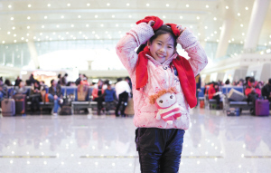 7岁的邹越小朋友戴着志愿者送的红色围巾和手套拗造型 