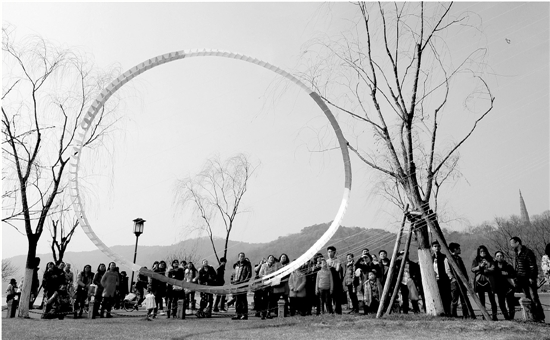 昨日杭城阳光灿烂，明显回暖。西湖白堤旁，一只彩色风筝吸引了众多游客。 里尔 摄 