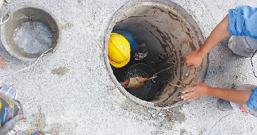 工作人员从雨水管道内吊起满满一桶淤泥。 