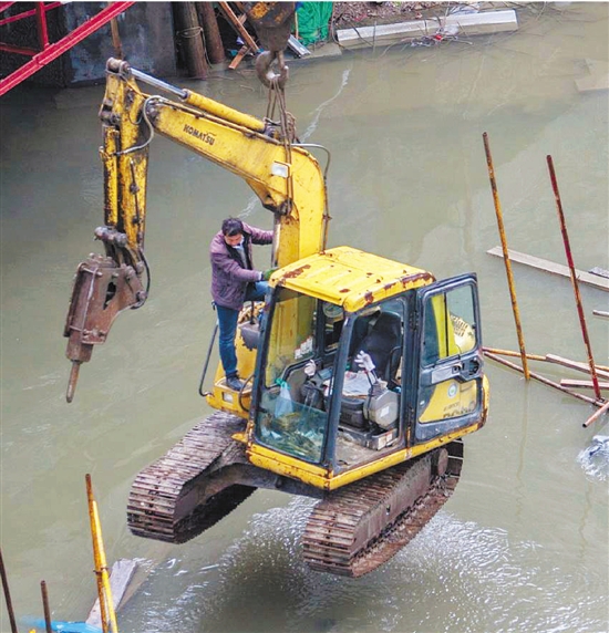 杭州东河边，凤起路地铁工地，2台挖掘机被满溢的东河河水困陷。昨天，施工方只得调来大型吊车将其吊离。