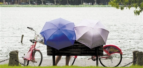 午后的西湖边，羞答答地落了几滴“太阳雨”，一手雨伞一眼美景。 里尔/摄