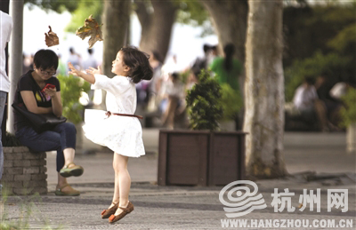 湖滨路，一个小女孩拿着两片落叶玩。记者 朱丹阳 摄