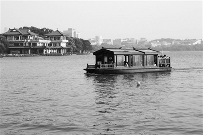 昨天下午，一艘断桥渡船驶过白堤湖面。记者 葛亚琪 摄