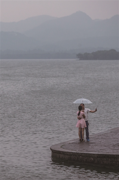 昨天傍晚，大雨突至，一对情侣在西湖边撑着伞自拍。 记者 陈中秋 摄