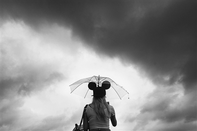 昨天下午，受台风“尼伯特”外围影响，西湖边下起了雨，一个戴米老鼠帽子的女孩撑伞游玩。 记者 陈中秋 摄