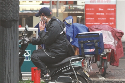 中山北路屏风街路口，一位外卖小哥边打着电话边骑车。