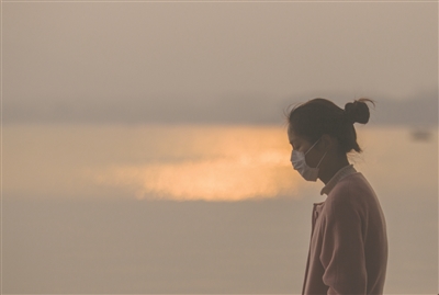 昨晚雾霾来袭，一位姑娘戴着口罩行走在西湖边。