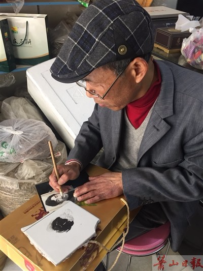     修版师朱师傅坐在店里修图，他把一盒铁皮枫斗垫在腿上当工作台。