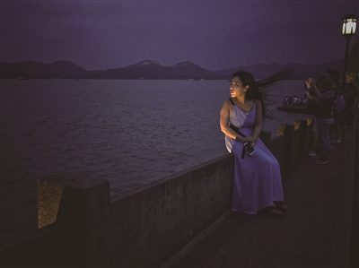 2016年8月11日，杭州，一名女游客坐在断桥上欣赏西湖夜景。 