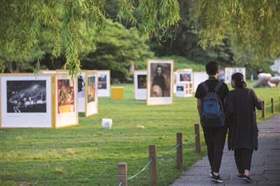 昨天下午，游客走过西湖孤山草坪的市民摄影节展览现场。