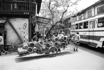 1976年4月，杭州华光巷，一位车夫拉着满车的陶罐，一辆公交车从他身旁驶过。 阿德里亚诺·马达罗 作品