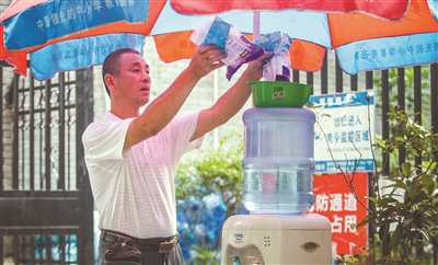 青年路送水站老板杨印军正在给免费供水点添加一次性杯子 