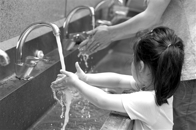 吃午饭前，一个小女孩跟着爸爸洗手。