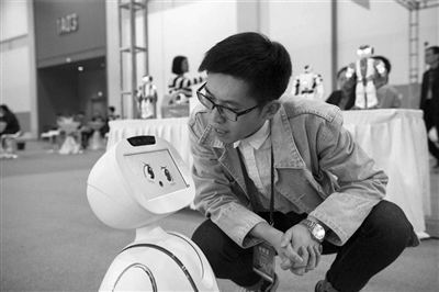 首届人工智能和智慧休闲展上，工作人员正在跟萌萌的机器人对话。
