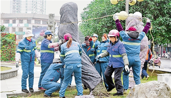 1月23日，在建德市新安江城区新世纪广场，园林工人正在给铁树穿上“棉衣”。 拍友 宁文武 摄
