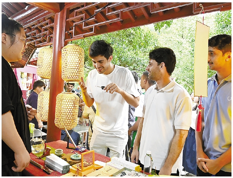 中外游客在满觉陇赏桂非遗市集品味美食、参与互动。