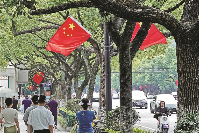 近日,一面面鲜艳的五星红旗在黄龙路沿线的路灯杆上迎风飘扬。