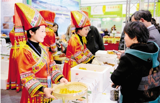 来自广西的水果经销商，身着民族服饰，请杭城市民品尝滑皮金桔。 本报记者 董旭明 摄