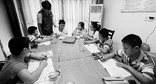 志愿者正在义务辅导“小候鸟”们做暑假作业。 